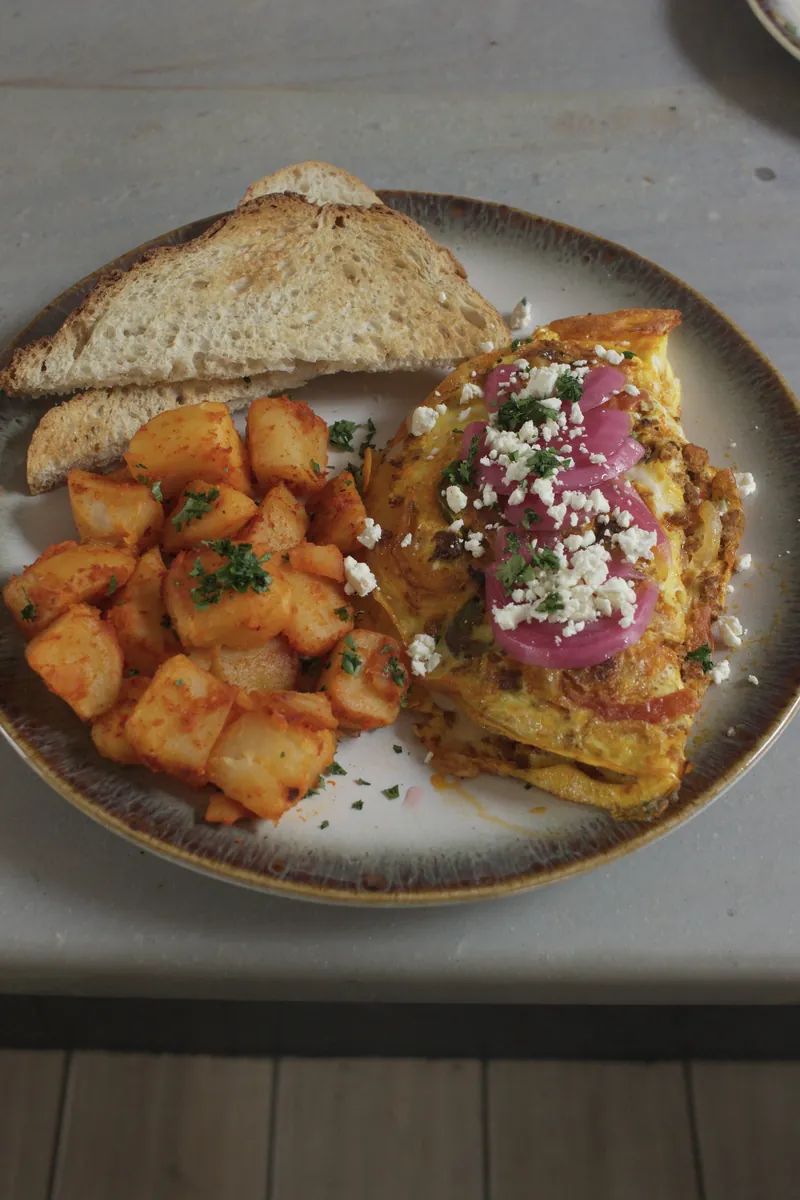 Chorizo omelette topped with feta and pickled red onion, with seasoned home fries and sourdough toast