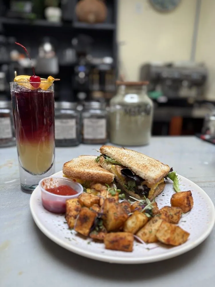 Breakfast sandwich with herb potatoes and sunrise cocktail